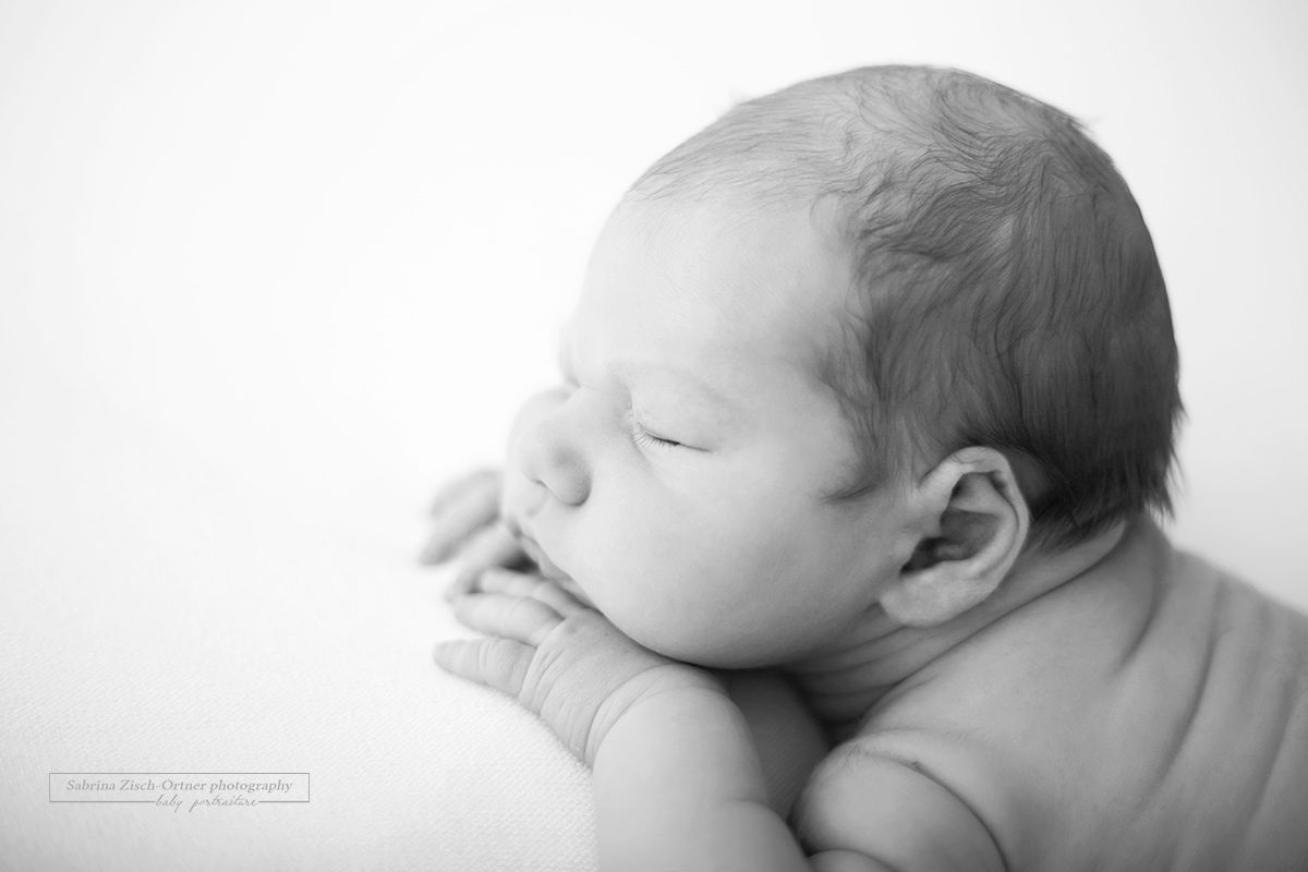 seitliches Nahaufnahme Portrait welches das süße Gesicht die kleinen Finger, sowie Schulter eines Neugeborenen zeigt gemacht von der Fotografin Sabrina