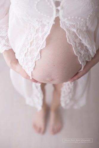 Babybauch von oben fotografiert umhüllt in einem am Bauch offenen Seidenkleid
