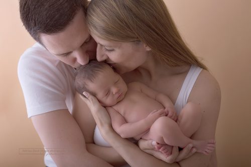 Eltern küssen ihre neugeborene Tochter auf der Stirn
