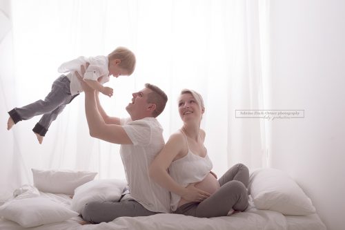 lachendes Familienfoto mit Babybauch, fliegendem großen Bruder und glücklichen Eltern bei Sabrina Zisch-Ortner photography