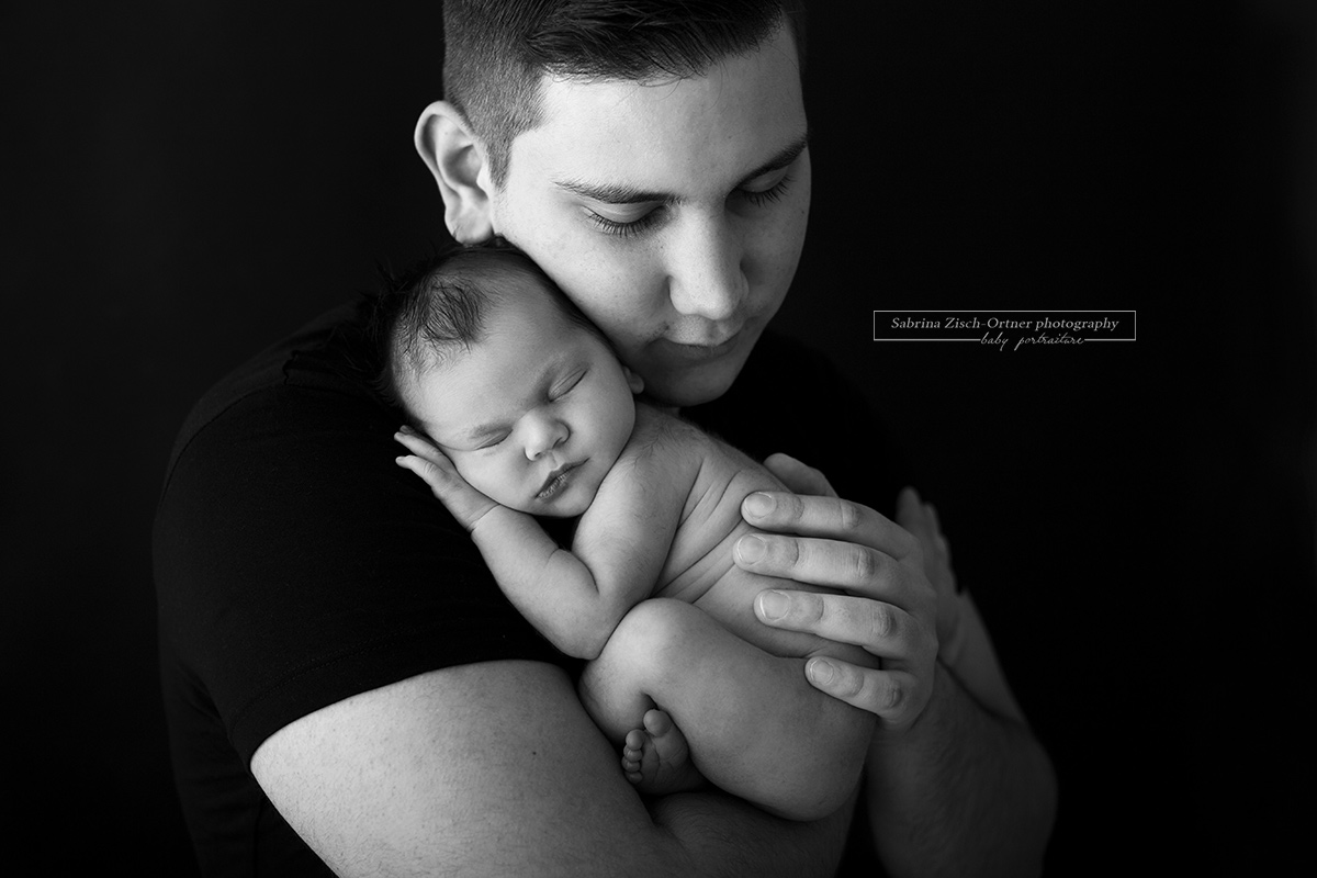 Kuschelfoto zwischen Papa und Baby erstellt während eines Neugeborenen Fotoshooting