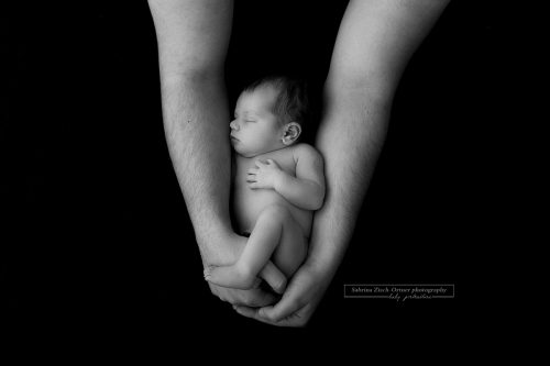 Schwarzweiß Foto bei welchem der Papa seine Tochter beschützend umhüllt mit seinen Händen