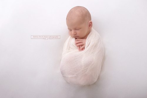 Das Baby wurde gemütlich und kuschelig eingewickelt in einen weißen Wrap
