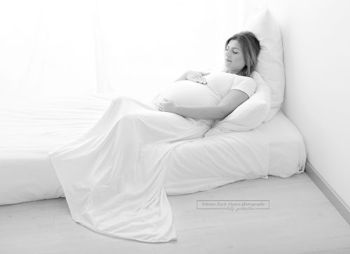 Schwangere liegend am Bett beim Schwangerschaftsfotoshooting bei Sabrina Zisch-Ortner