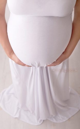 Schwangerschaftbauch eingehüllt im weißem Kleid im Großformat