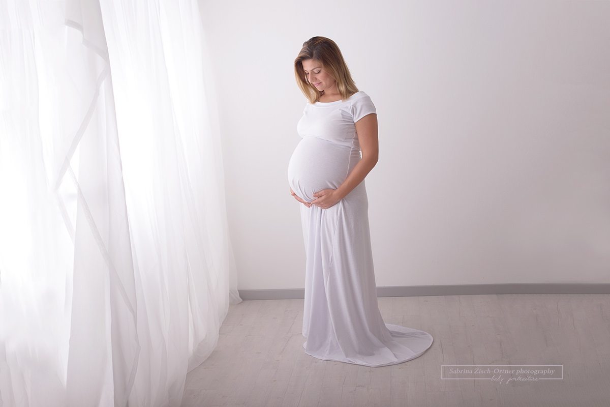 Ein kugelrunder Schwangerschaftsbauch im neuen weißen Babybauchkleid