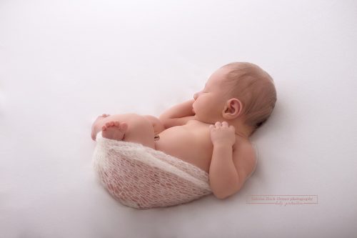 Neugeborene ist eingekuschelt in ein kleines weißen Nestchen