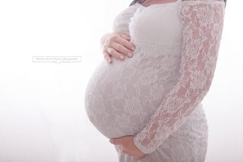 kugelrunde Babybauch in Spitzenkleid von der Seite fotografiert