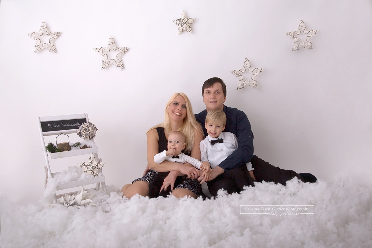 Familienfoto im weihnachtlichen Schnee Setup mit hängenden Sternen