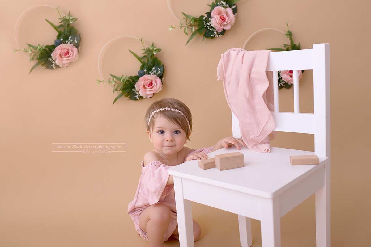 Süßes einjähriges Mädchen im Blumen Setup beim Fotoshooting