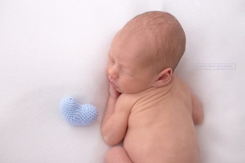 Blaues handgemachtes gehäkeltes Herz neben kleinen Baby