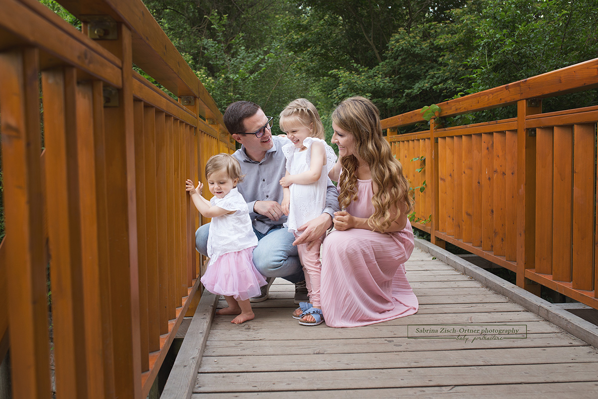 Wunderhübsches Familienfoto auf einer braunrötlichen Brücke