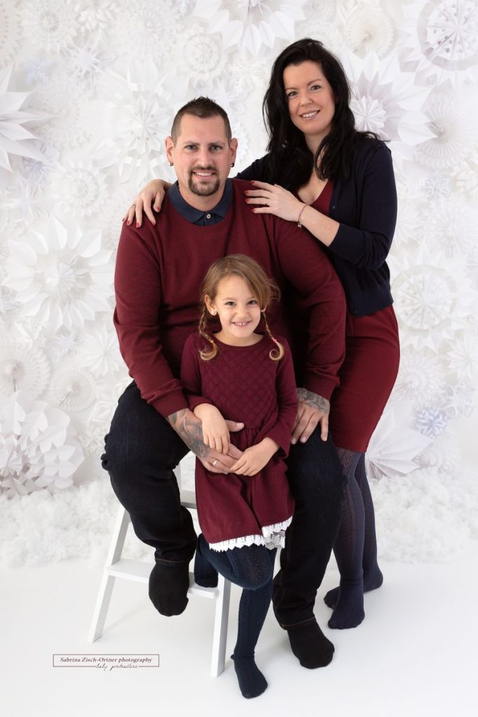 Familie in Rot vor den weißen Schneeflocken bei ihrem Fotoshooting