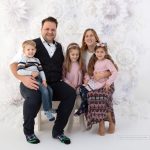 Fünfköpfige Familie strahlt in die Kamera bei ihrem Weihnachtsmini Termin