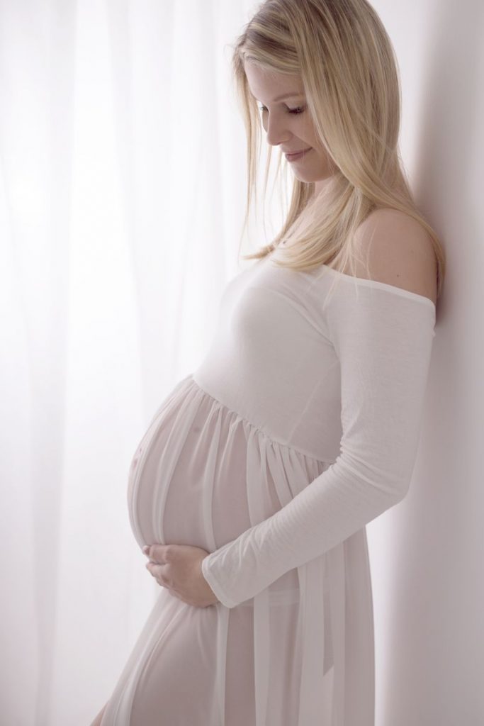Foto der Erstlingsmama in einem hübschen weißen Schwangerschaftskleid