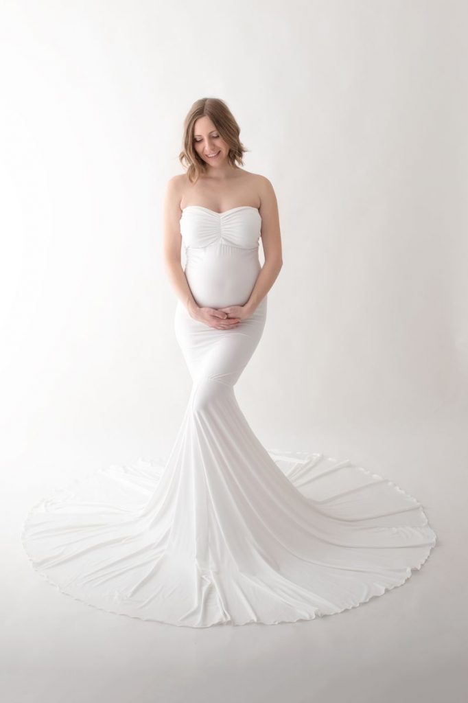 FAQ Babybauch Shooting Foto zeigt eine strahlende und glückliche Schwangere im Fotostudio
