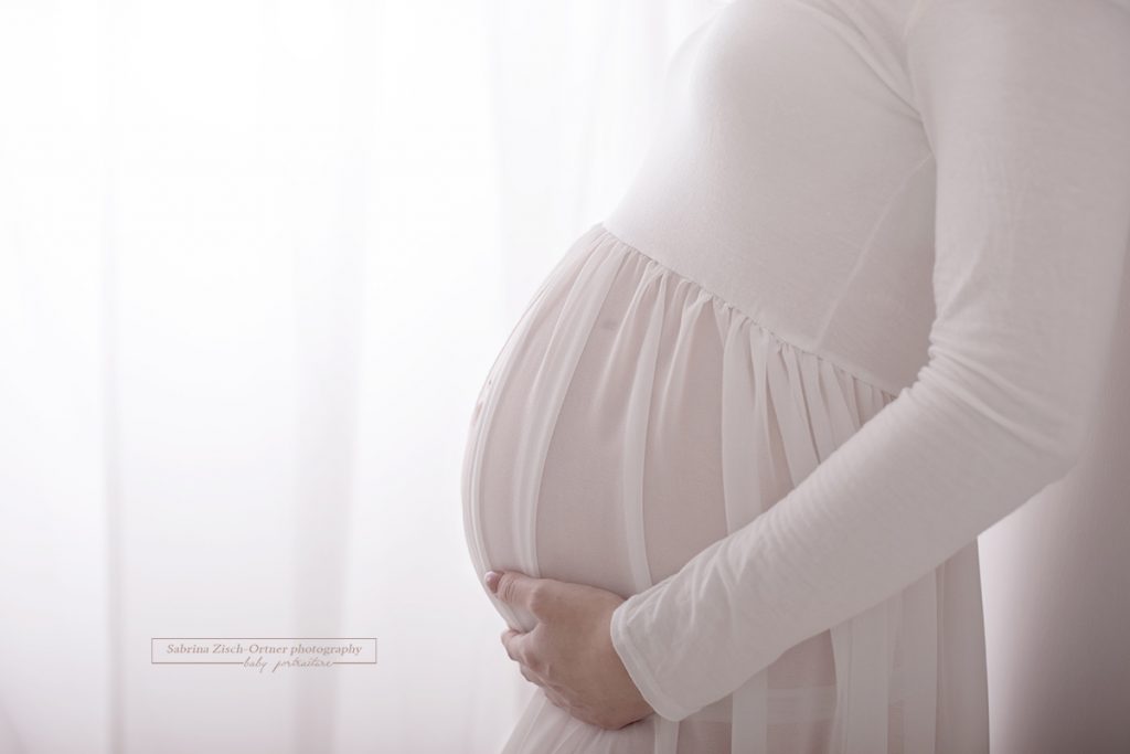 Babybauch versteckt unter dem leicht durchsichtigen Schwangerschaftskleid