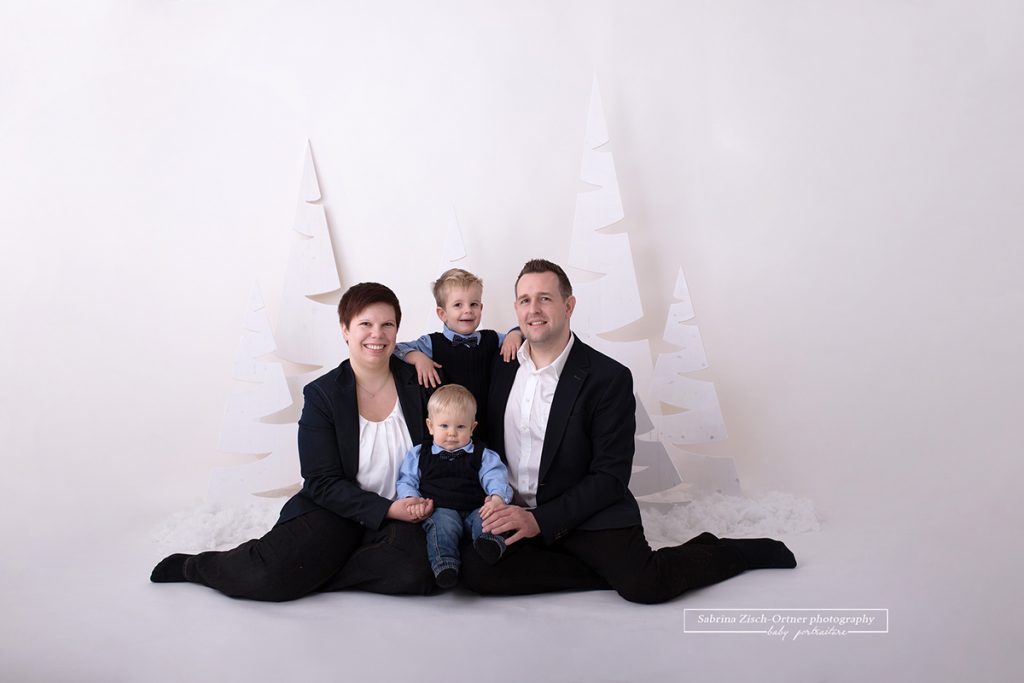 sitzendes Familienfoto mit Anzug und Mascherl im vorbereiteten und selbst ausgedachten Weihnachtssetup