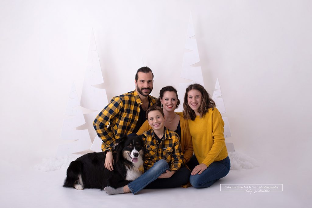 Familienfoto im sitzen vor den 180m hohen Weihnachtsbäumen mit Hund und Teenagern