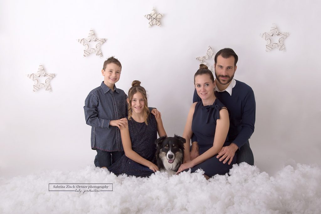 Weihnachtsfamilienfoto mit ihrem Hund in der Mitte