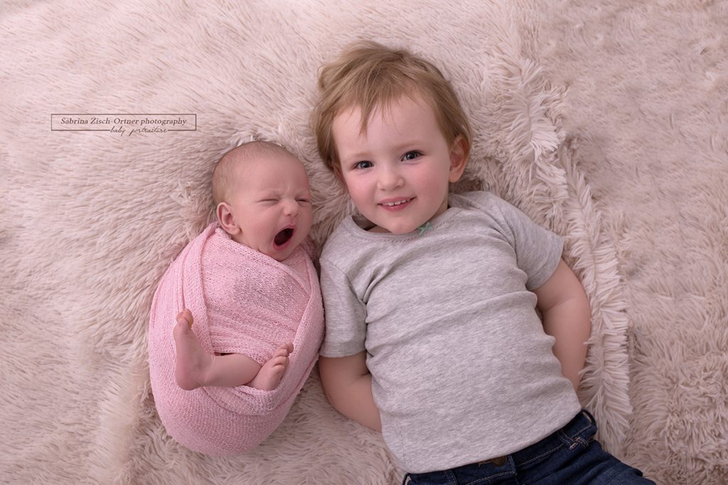 lächelndes Geschwisterfoto als Highlight bei einem Neugeborenen Fotoshooting