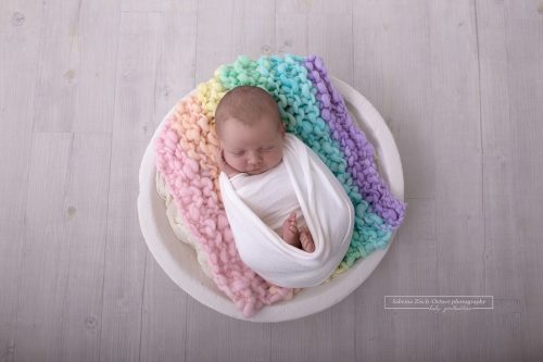 Baby auf Decke aus Regenbogenfarben in weissen Schalen
