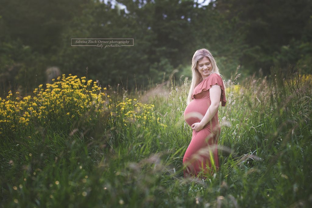 Babybauch der lachenden bald Mama blitzt in der Naturwiese hervor
