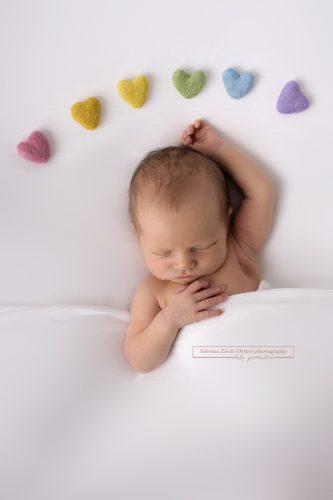 Filz Herzen in Regenbogenfarben und neugeborenes Baby