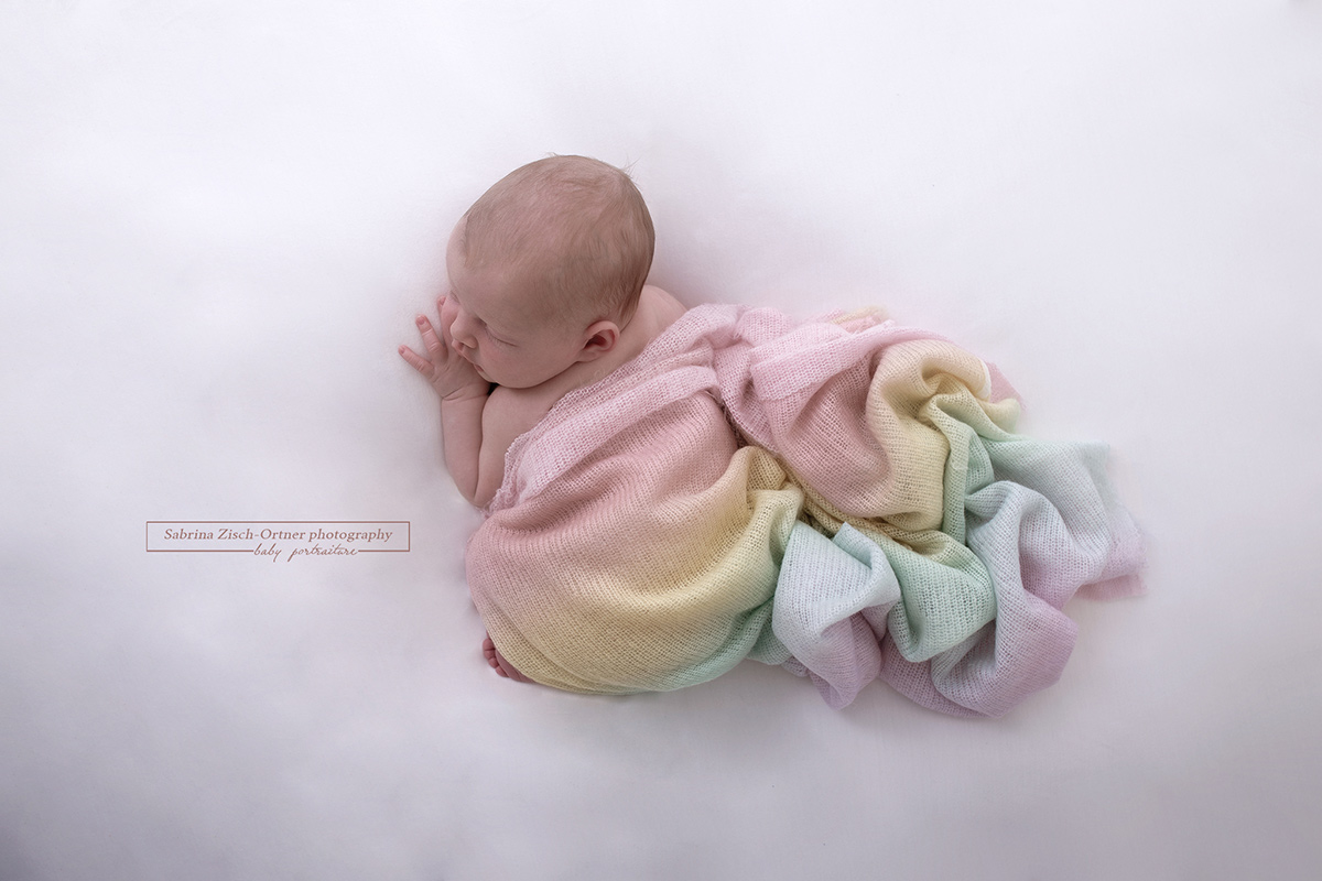 Foto von oben gemacht mit Blick auf Baby und Tuch in Regenbogenfarben