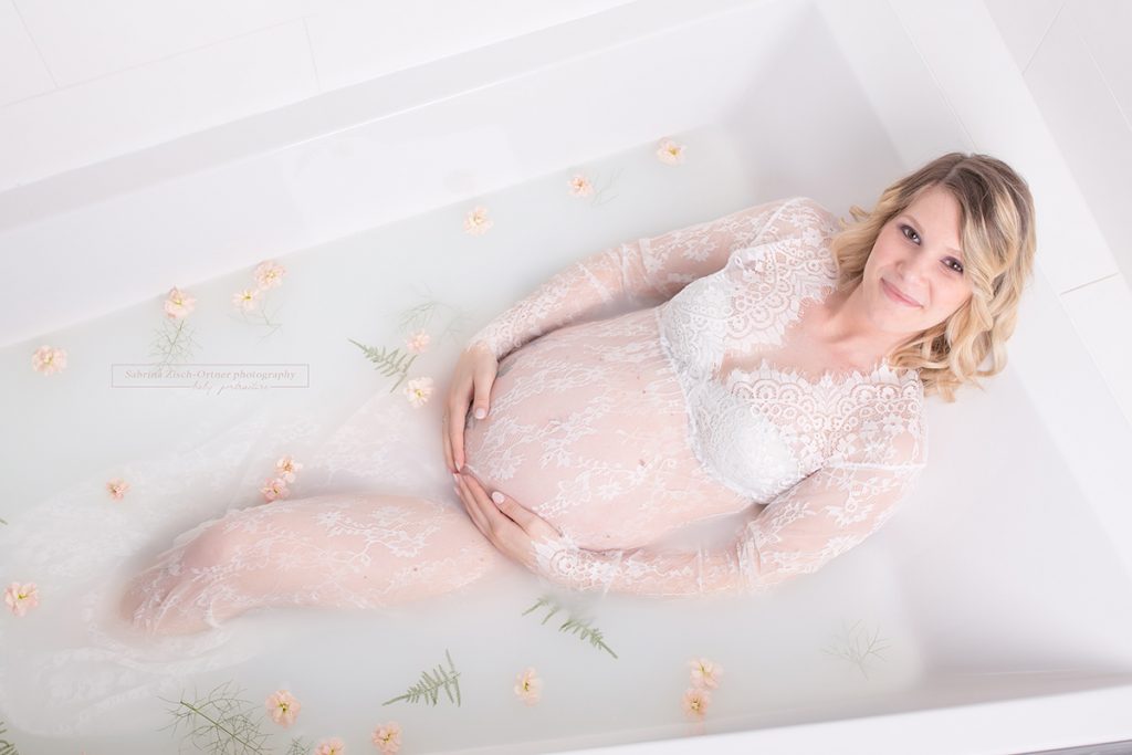 hübsch strahlende Schwangere liegt gemütlich in ihrem Milchbad