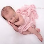 schlafendes Baby bei Fotoshooting mit Rosa Tuch umhüllt