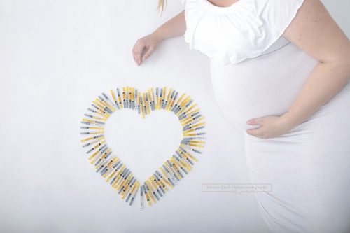 Herz aus Hormon Spritzen der künstlichen Befruchtung IVF neben dem Babybauch der Baldmama