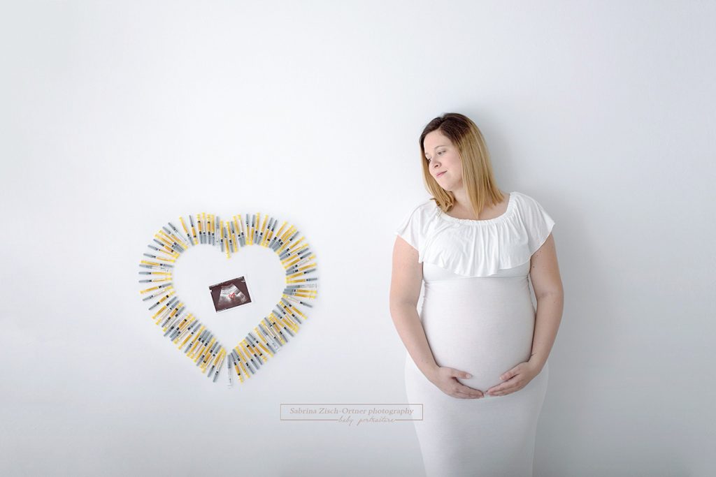 Ultraschallbild inmitten einem Herz aus Spritzen einer künstlichen Befruchtung mit glücklichen Schwangeren