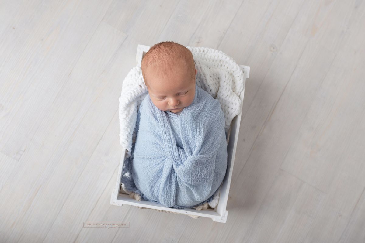 Baby mit blauen Tuch gewrapped in Kiste