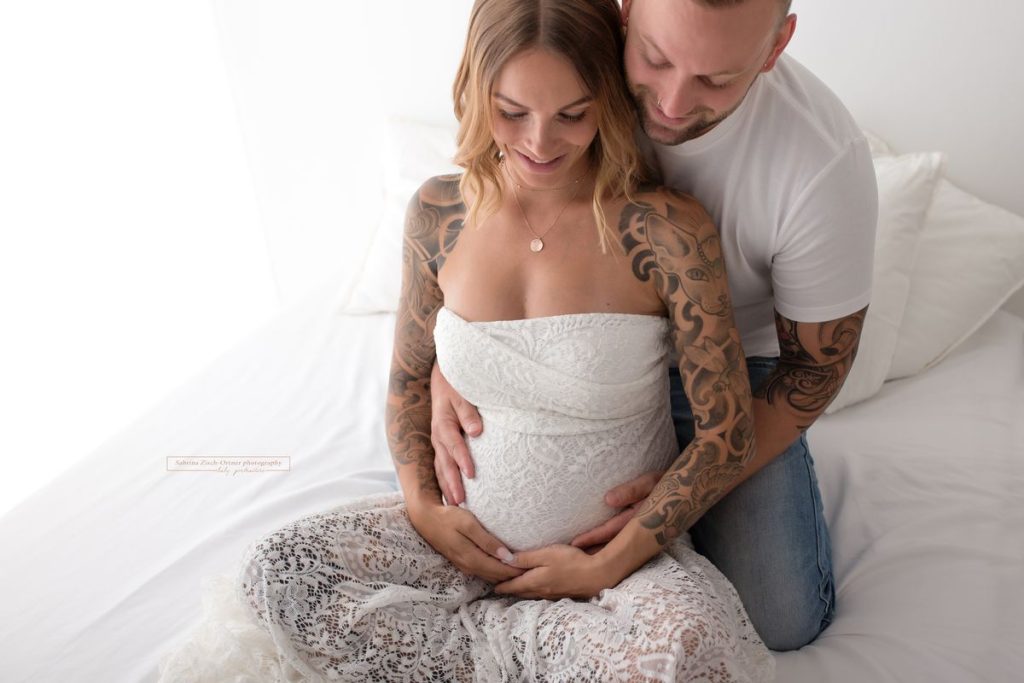 Familienfoto mit Babybauch in Spitze und hervorstechenden Tattoos