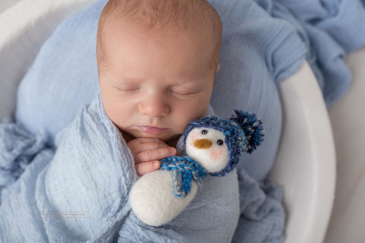 Neugeborenes Baby mit Schneemann aus Filz