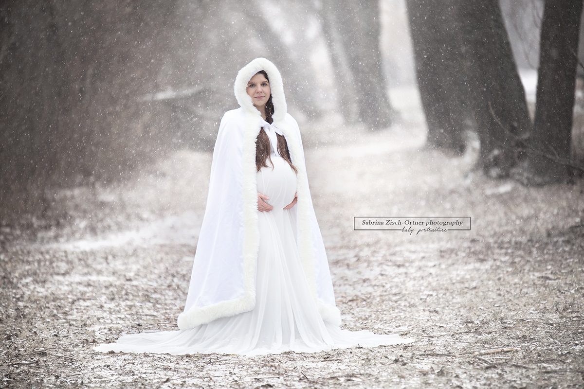 Schwangere bei ihrem Fotoshooting in der freien Natur im Winter bei Schneefall