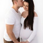 Schwangere bekommt Kuss auf die Stirn von ihrem Mann