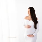 Schwangere im engen weißen Babybauchkleid mit offenen langen schwarzen Haaren