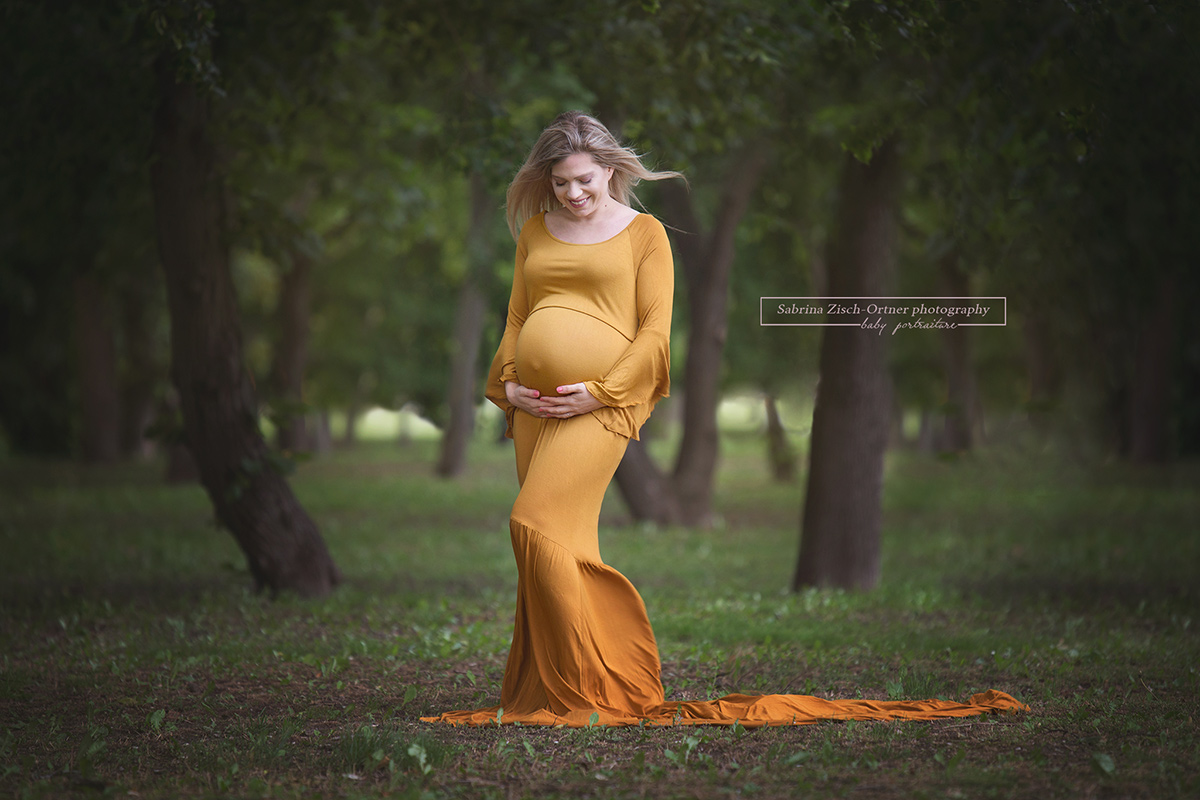 Schwangerschaftsshooting im gelben Babybauchkleid inmitten der grünen Natur