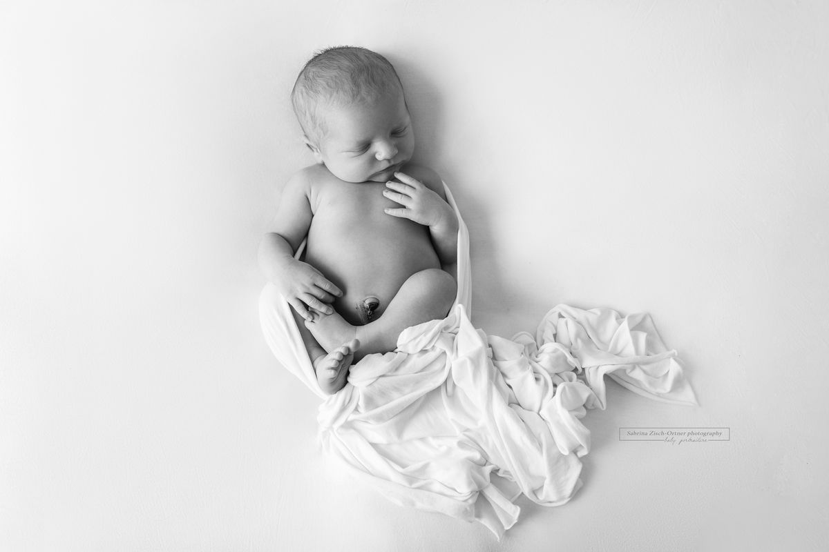 neugeborener Junge mit Tuch eingewickelt in Schwarz Weiß