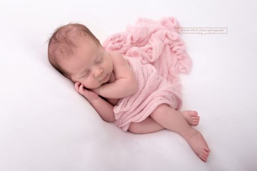schlafendes Baby bei Fotoshooting mit Rosa Tuch umhüllt