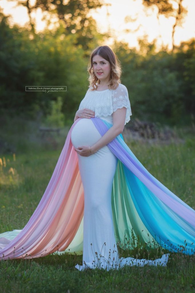 weißes Babybauchkleid und Regenbogenfarbenrock beim Schwangerschaftsshooting