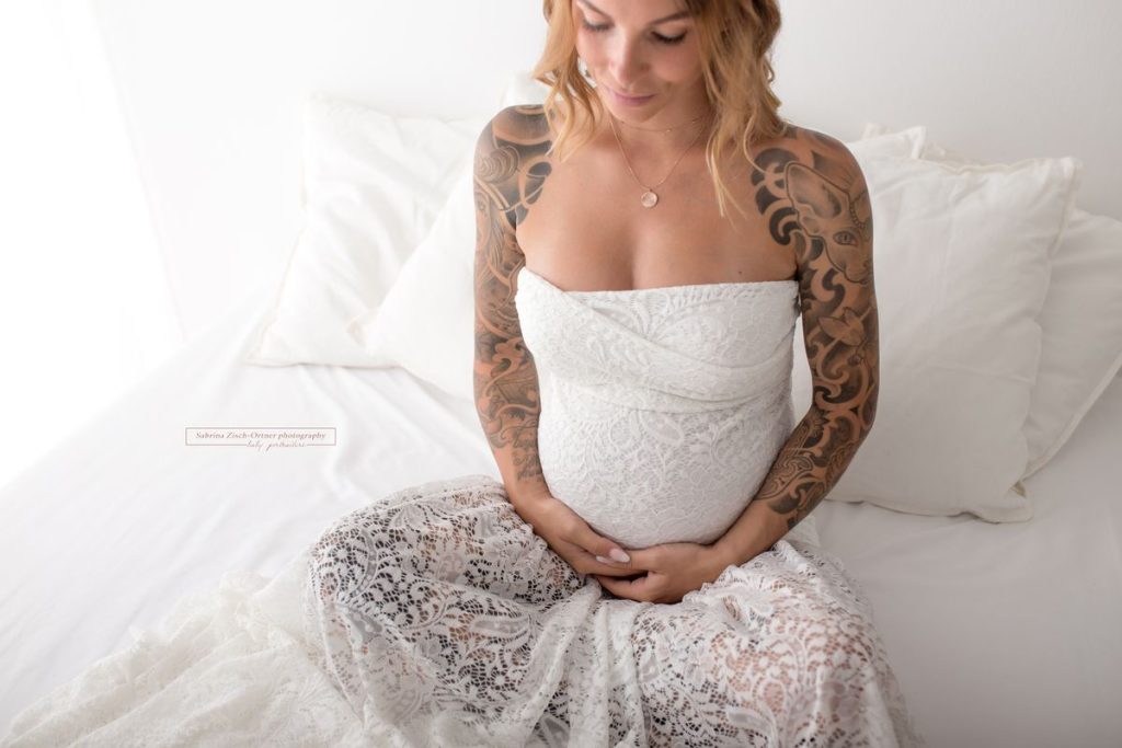 zarte Schwangere im handgemachten Spitzenkleid beim Babybauchshooting in Wien