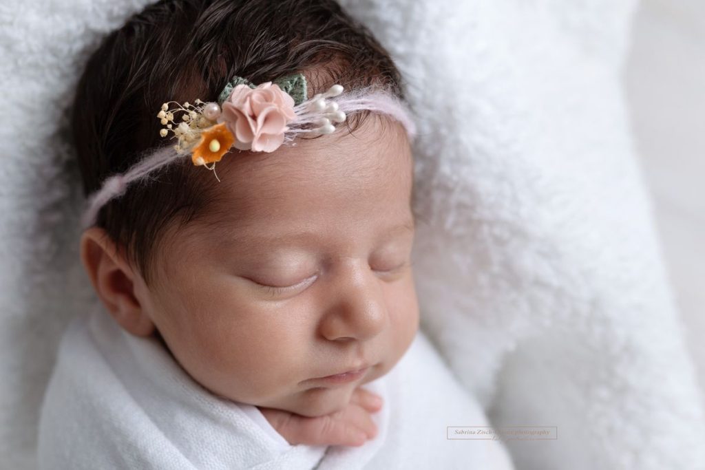 Baby Mädchen mit rosa Haarband mit Blüten