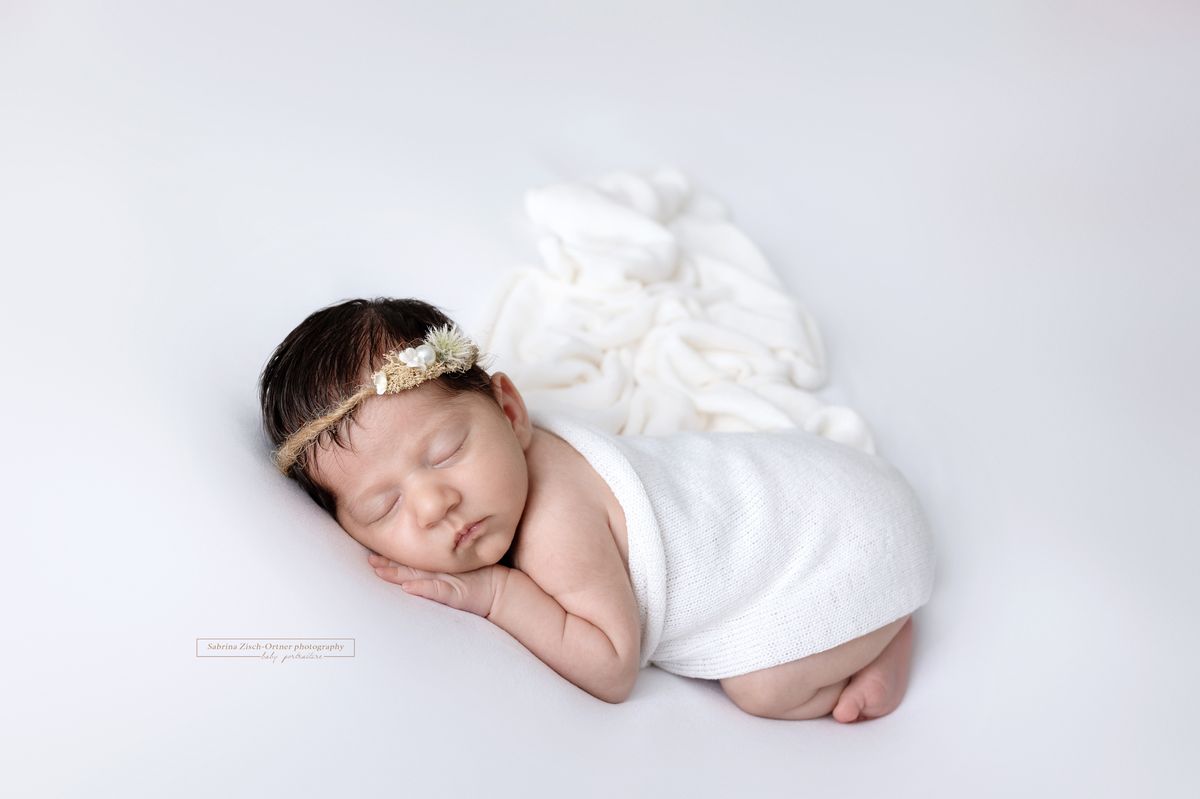 Baby Neugeborenes mit weißem Tuch und Haarband