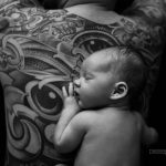 Baby liegt auf tätowierten Rücken des Papas