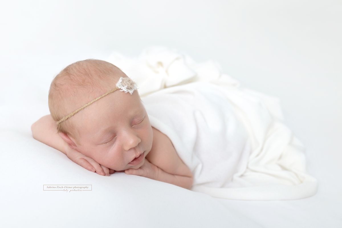 Babyshooting Mädchen in weißem Tuch mit zartem Haarband