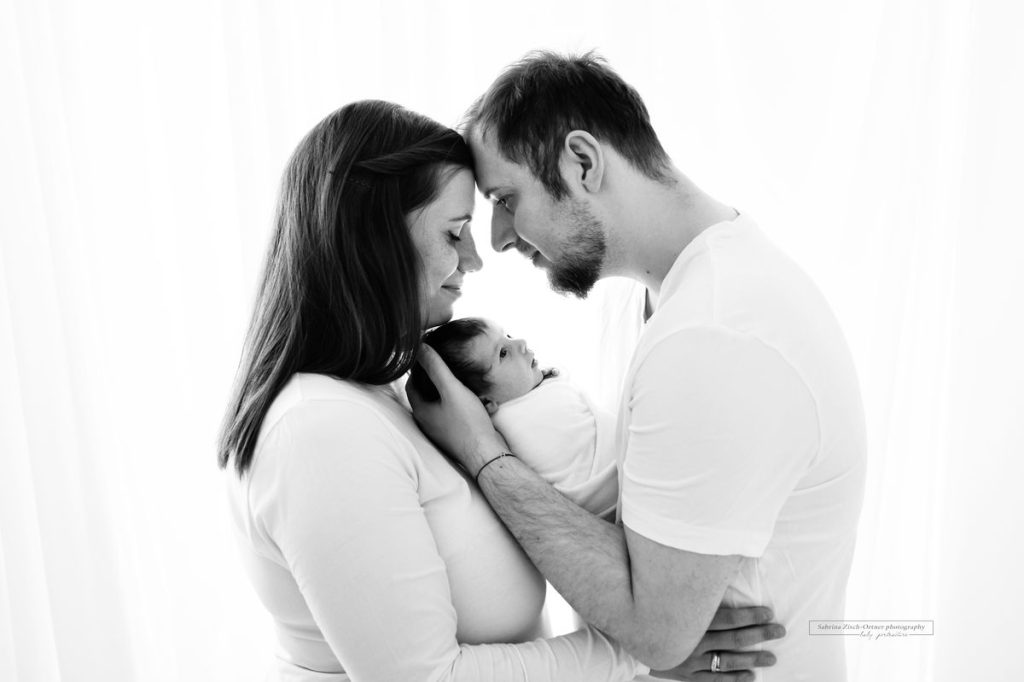 Familienfoto der glücklichen Eltern mit frischgeschlüpften neugeborenen Baby Tochter in Schwarz Weiß