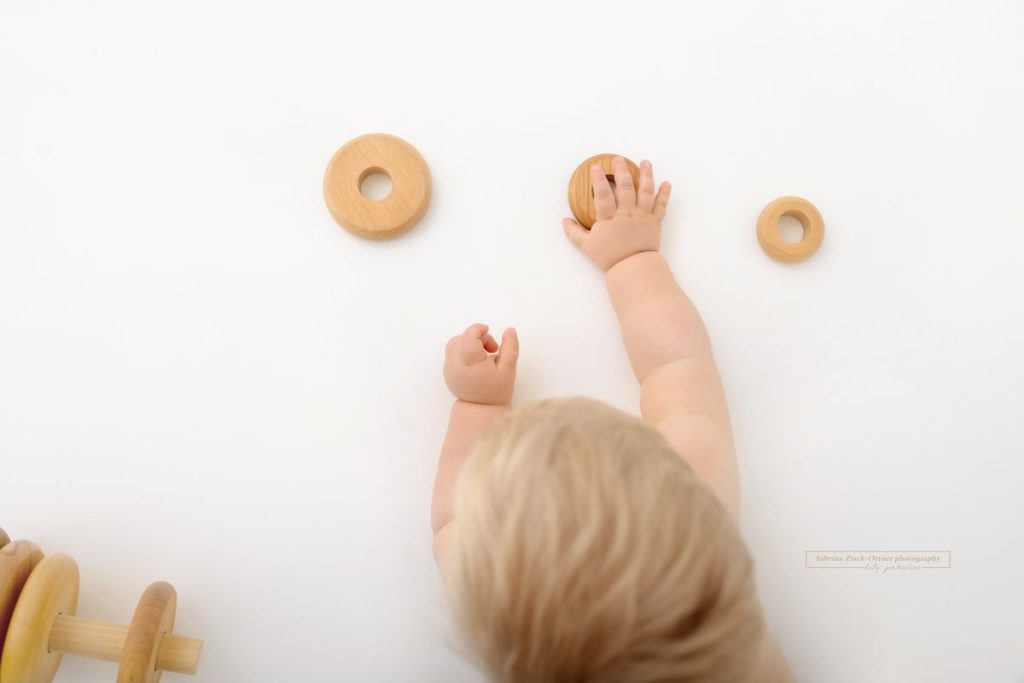 Holz Spielzeug und kleine Kinder Hände festgehalten beim Babyshooting